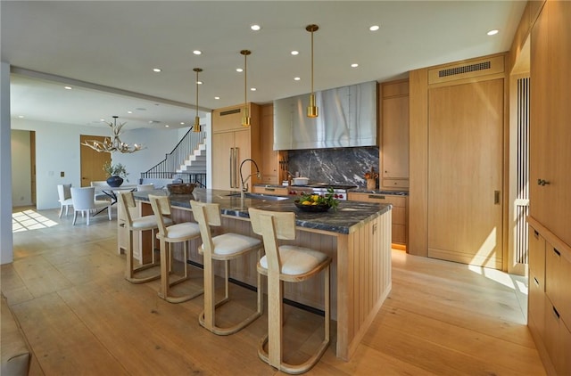 kitchen with decorative light fixtures, a large island with sink, sink, and a kitchen breakfast bar