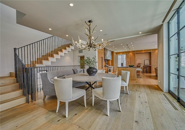 dining space featuring light wood-type flooring and an inviting chandelier