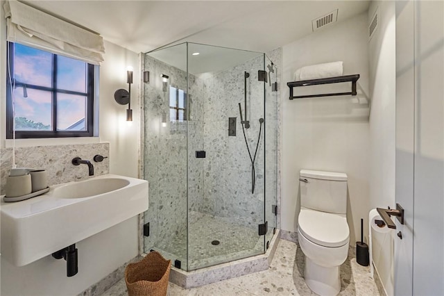 bathroom featuring sink, toilet, and a shower with door