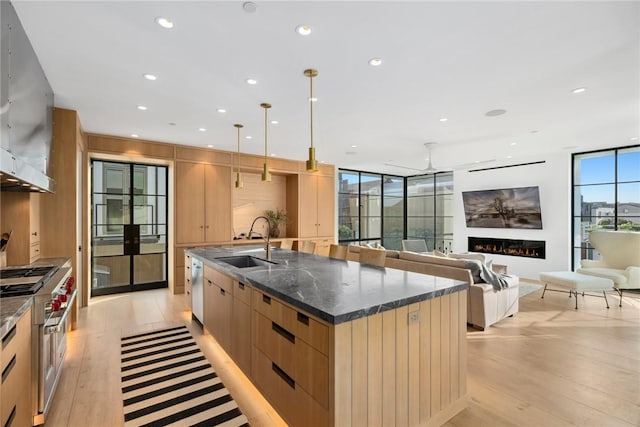 kitchen with a large island, sink, decorative light fixtures, light hardwood / wood-style flooring, and range with two ovens