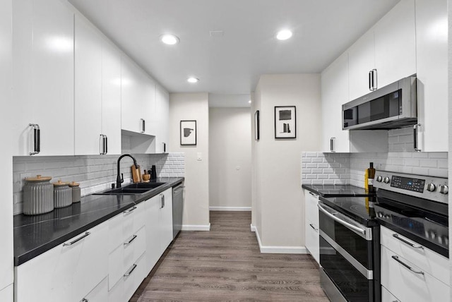 kitchen featuring sink, dark hardwood / wood-style floors, stainless steel appliances, decorative backsplash, and white cabinets