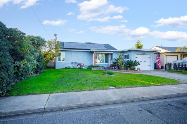 single story home with a garage, a front yard, and solar panels