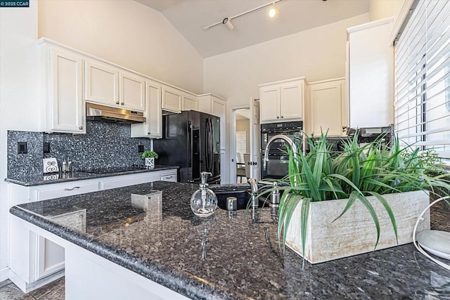 kitchen featuring vaulted ceiling, white cabinets, decorative backsplash, dark stone counters, and black appliances