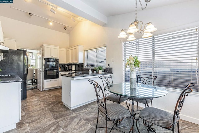 dining room with lofted ceiling, a notable chandelier, rail lighting, and sink