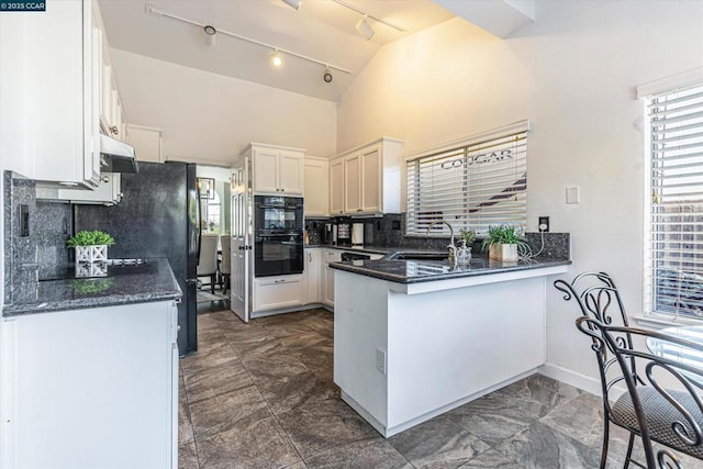 kitchen featuring double oven, white cabinetry, lofted ceiling, sink, and kitchen peninsula