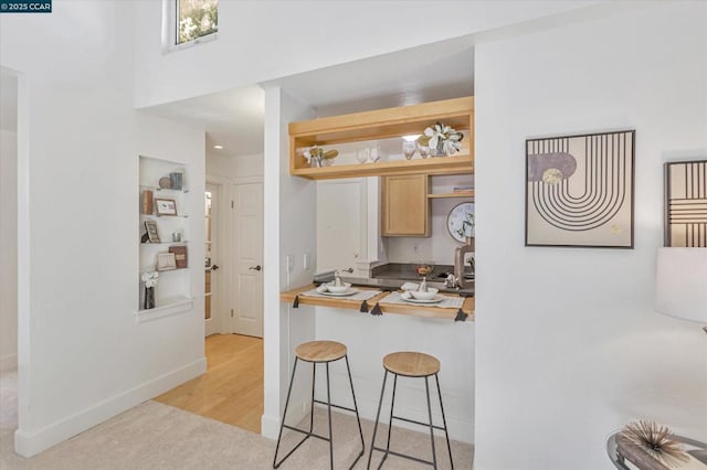 kitchen featuring a breakfast bar, light colored carpet, and wooden counters