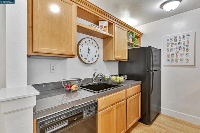 kitchen featuring black appliances, light brown cabinetry, tile counters, sink, and light hardwood / wood-style flooring