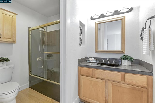 full bathroom with wood-type flooring, toilet, shower / bath combination with glass door, and vanity