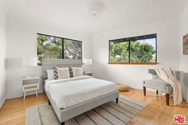 bedroom with multiple windows, hardwood / wood-style flooring, and ornamental molding