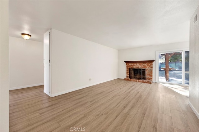 unfurnished living room featuring light hardwood / wood-style floors and a brick fireplace