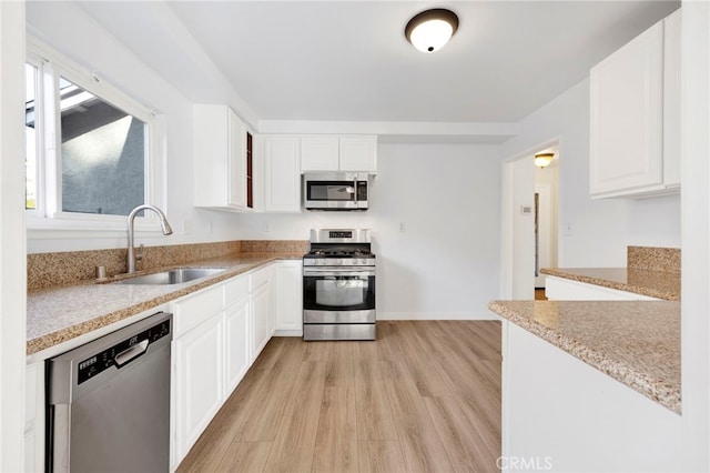 kitchen with sink, stainless steel appliances, white cabinets, and light stone countertops