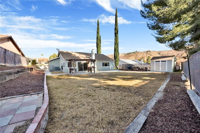 rear view of house with a yard, a patio, and a storage unit