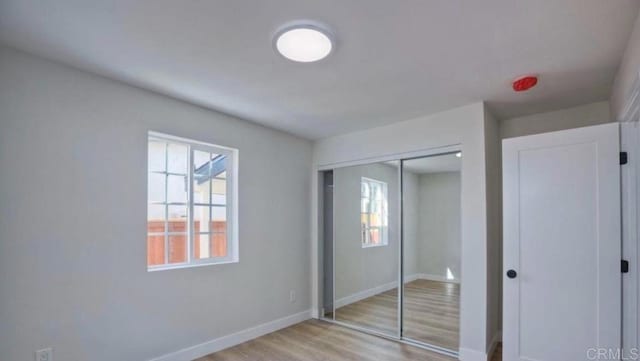 unfurnished bedroom with multiple windows, a closet, and light hardwood / wood-style flooring