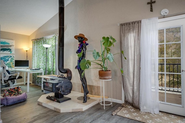 living area with lofted ceiling, wood-type flooring, and a wood stove