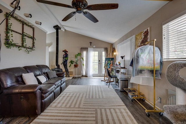 living room featuring dark wood-type flooring, lofted ceiling with beams, ceiling fan, and a wood stove