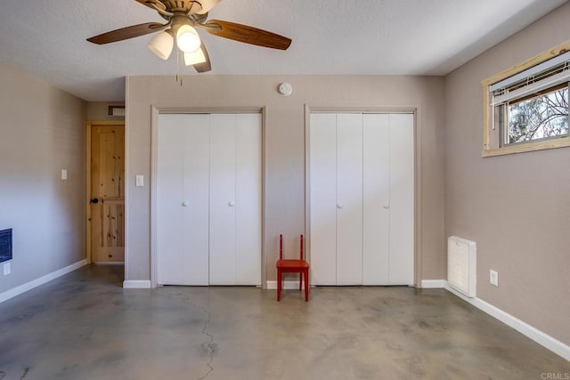 unfurnished bedroom featuring ceiling fan, concrete flooring, and two closets