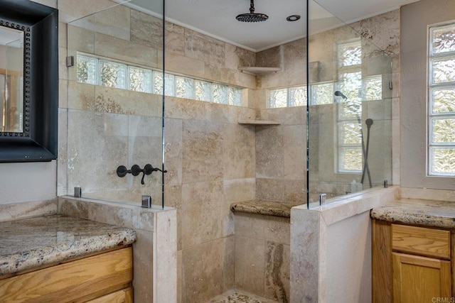 bathroom with tiled shower, vanity, and a wealth of natural light