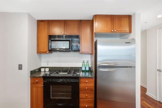 kitchen with black appliances, dark stone counters, and dark hardwood / wood-style floors