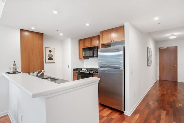 kitchen featuring dark hardwood / wood-style flooring, sink, black appliances, and kitchen peninsula