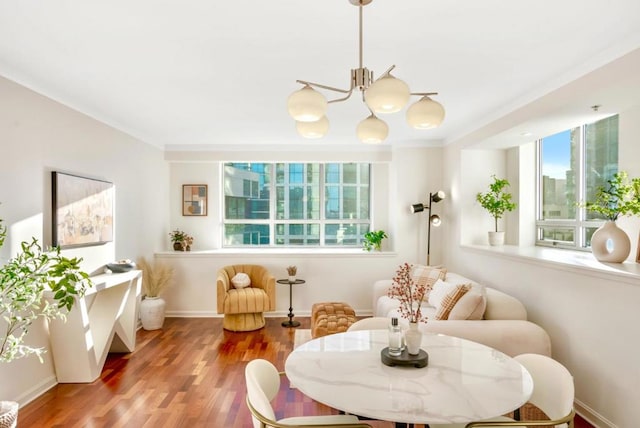 sitting room with ornamental molding, hardwood / wood-style floors, and an inviting chandelier