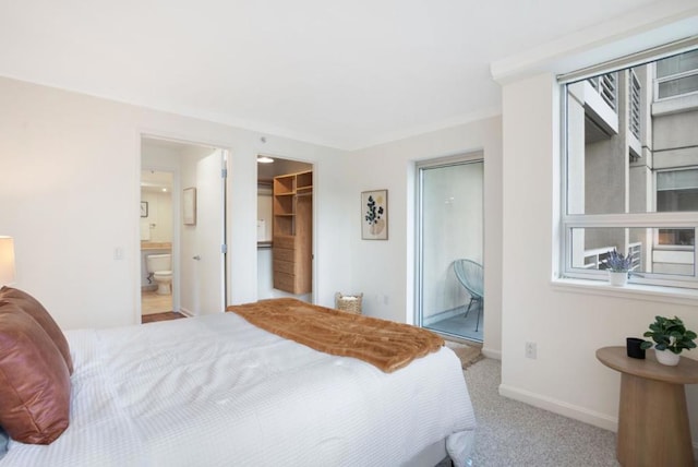 bedroom featuring light colored carpet, a closet, ensuite bathroom, and a walk in closet