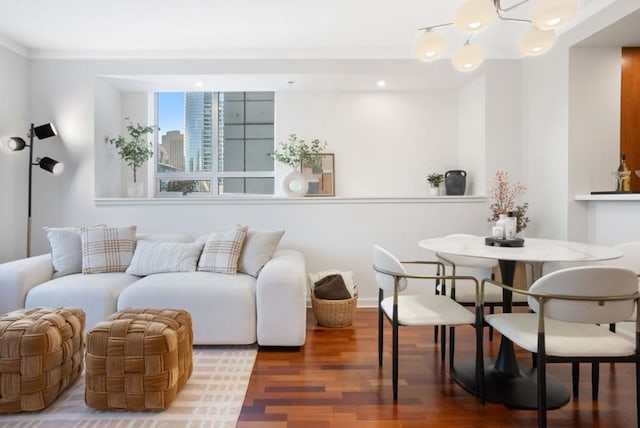 living room featuring wood-type flooring, crown molding, and an inviting chandelier