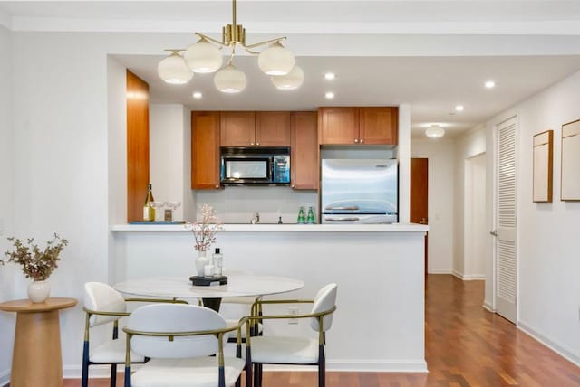 kitchen with stainless steel built in fridge, hardwood / wood-style flooring, and kitchen peninsula