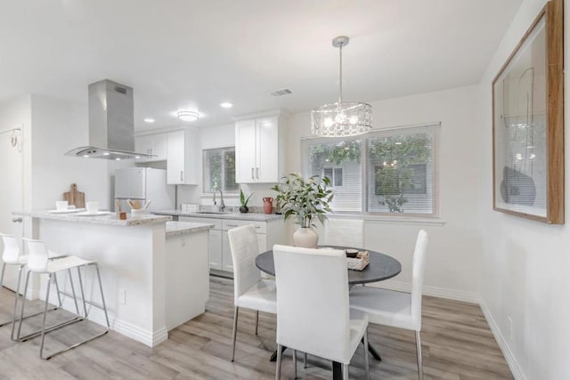 dining space featuring a chandelier, light hardwood / wood-style floors, and sink