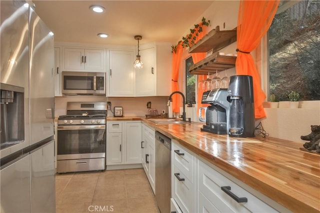 kitchen featuring white cabinetry, pendant lighting, butcher block counters, and stainless steel appliances