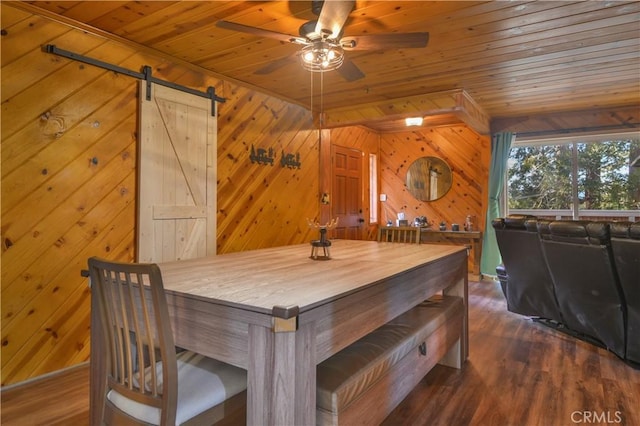 dining room featuring wood walls, wooden ceiling, and a barn door