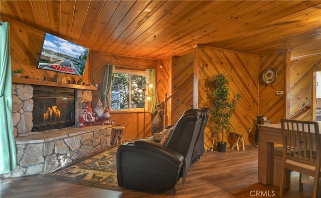 living area featuring hardwood / wood-style flooring, a stone fireplace, and wooden ceiling