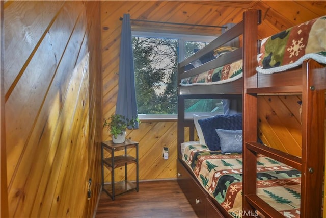 bedroom with wooden walls and dark hardwood / wood-style flooring