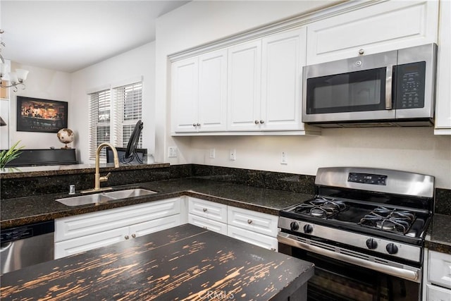 kitchen featuring white cabinetry, stainless steel appliances, sink, and dark stone counters