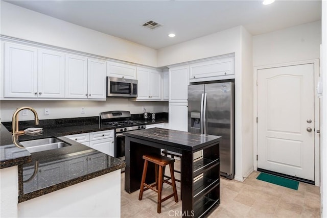 kitchen with white cabinetry, sink, dark stone counters, and appliances with stainless steel finishes