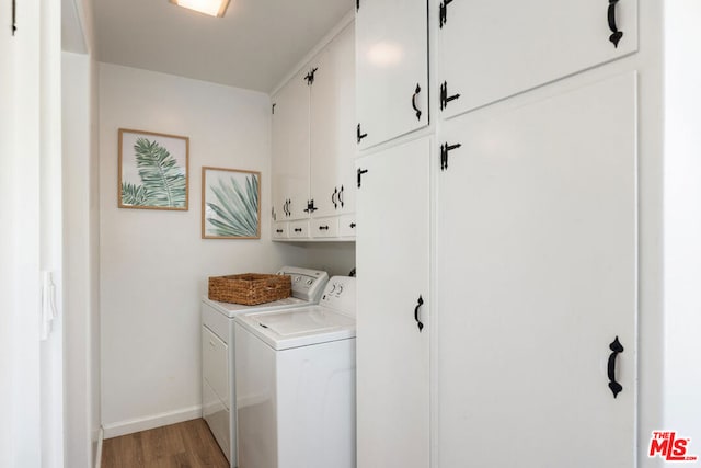 laundry room featuring washer and clothes dryer, light hardwood / wood-style floors, and cabinets