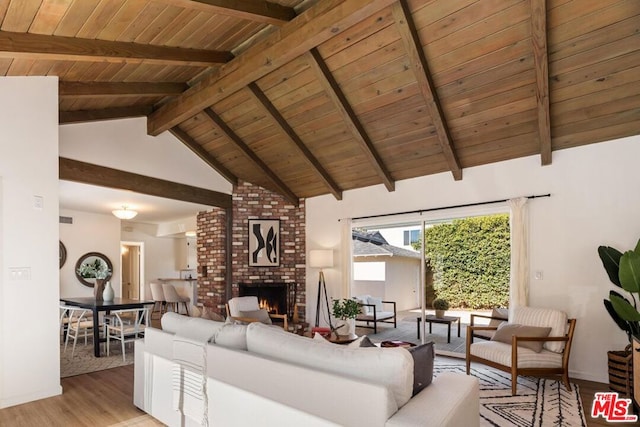 living room with wooden ceiling, a large fireplace, beam ceiling, and light wood-type flooring