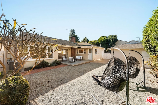 rear view of house featuring an outdoor living space and a patio area