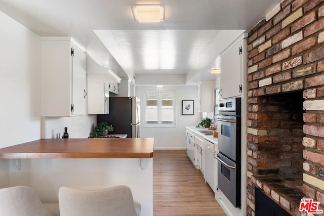 kitchen with a breakfast bar, white cabinets, kitchen peninsula, and appliances with stainless steel finishes