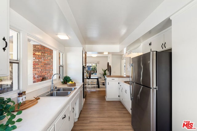 kitchen with sink, stainless steel refrigerator, white cabinets, and dark wood-type flooring