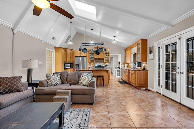 tiled living room with ceiling fan, beam ceiling, a skylight, and french doors