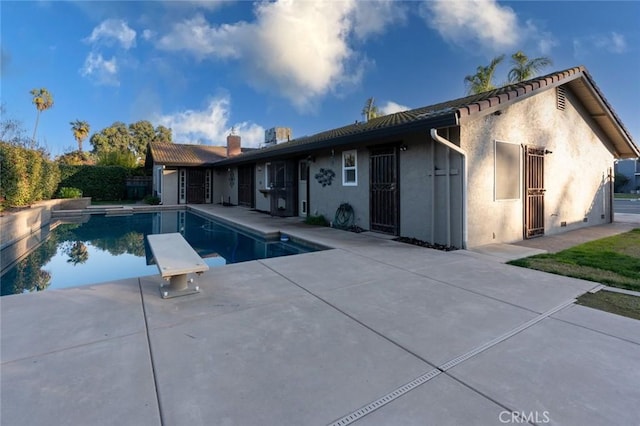 view of swimming pool with a diving board and a patio