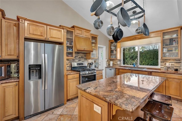 kitchen featuring appliances with stainless steel finishes, a center island, backsplash, vaulted ceiling, and a breakfast bar