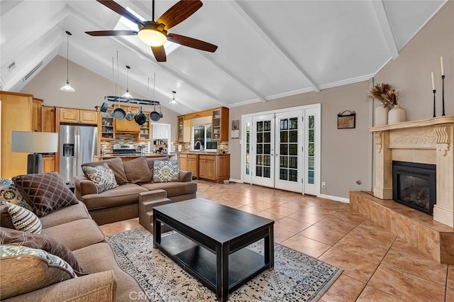 living room with sink, french doors, vaulted ceiling with beams, a tiled fireplace, and light tile patterned flooring