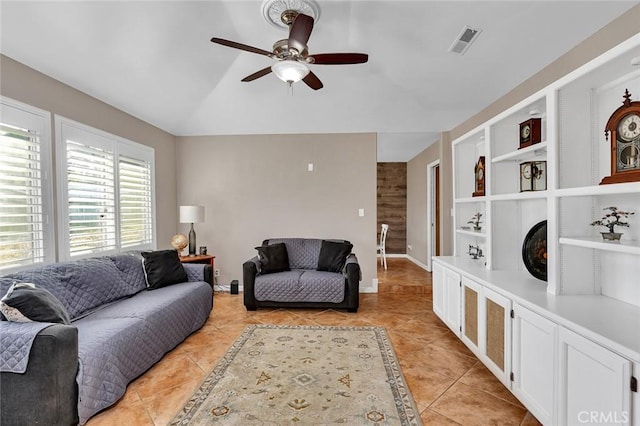 living room with built in features, ceiling fan, and light tile patterned floors