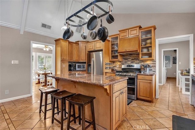 kitchen with a center island, stainless steel appliances, tasteful backsplash, dark stone countertops, and custom range hood