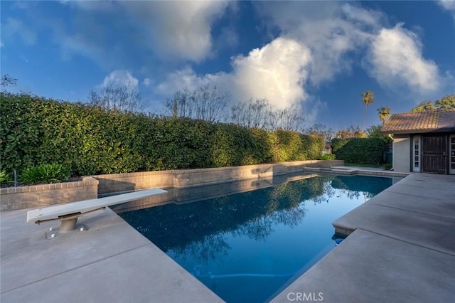 view of swimming pool with a patio area and a diving board