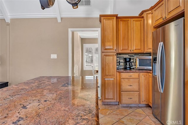 kitchen with crown molding, stainless steel fridge, tasteful backsplash, light tile patterned floors, and dark stone counters