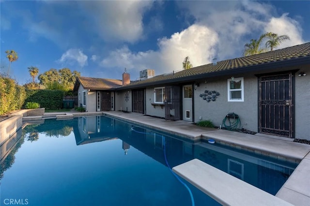 view of swimming pool with a diving board and a patio