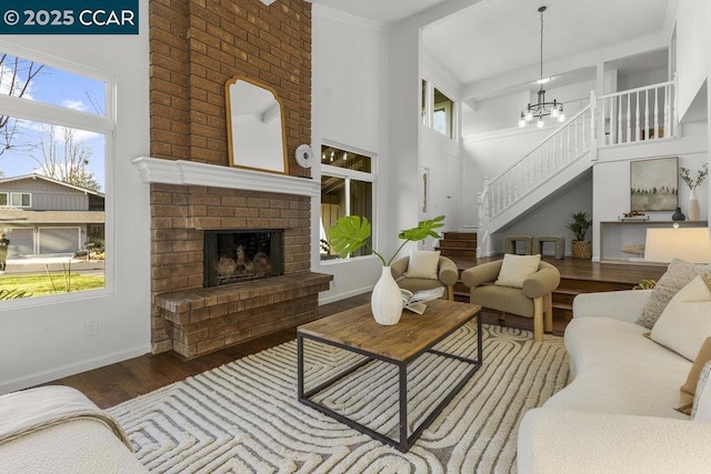 living room featuring hardwood / wood-style flooring, an inviting chandelier, a brick fireplace, and a wealth of natural light