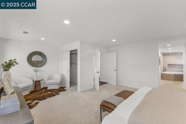 bedroom featuring light colored carpet, connected bathroom, and a closet